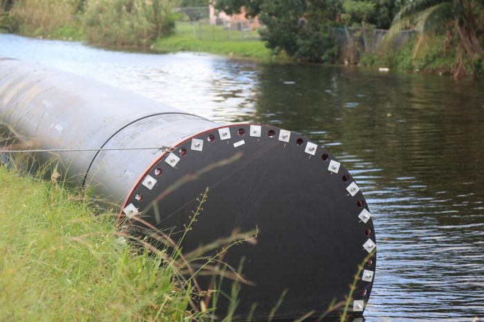 A large diameter 63-inch pipe tied to the side of a stream