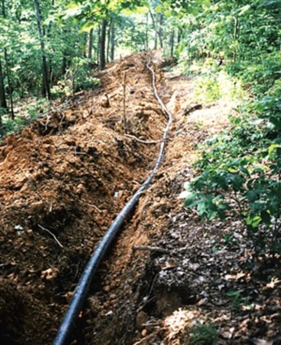 HDPE pipe in an excavated ditch running through woods in Dalton, Georgia